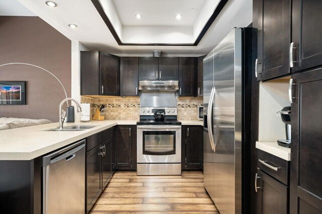 kitchen with light wood-type flooring, stainless steel appliances, backsplash, and sink