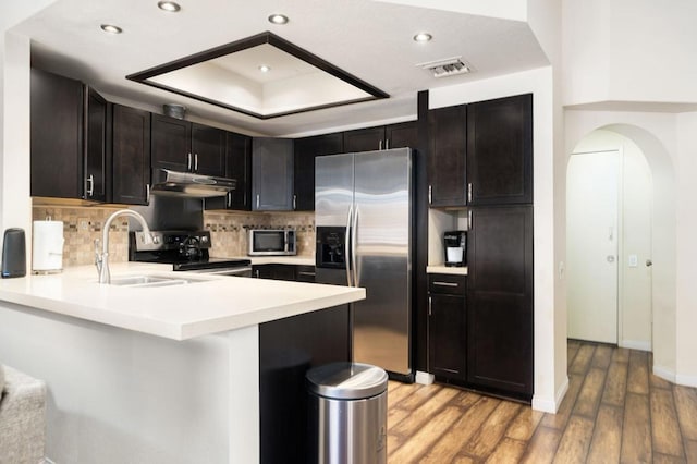 kitchen with sink, light hardwood / wood-style flooring, decorative backsplash, kitchen peninsula, and stainless steel appliances