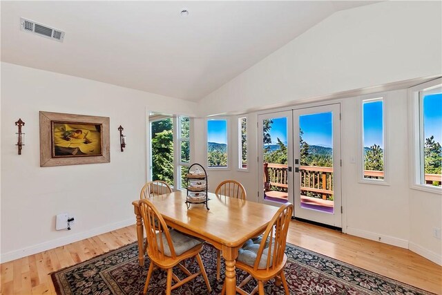 dining room featuring light wood-type flooring, lofted ceiling, and french doors