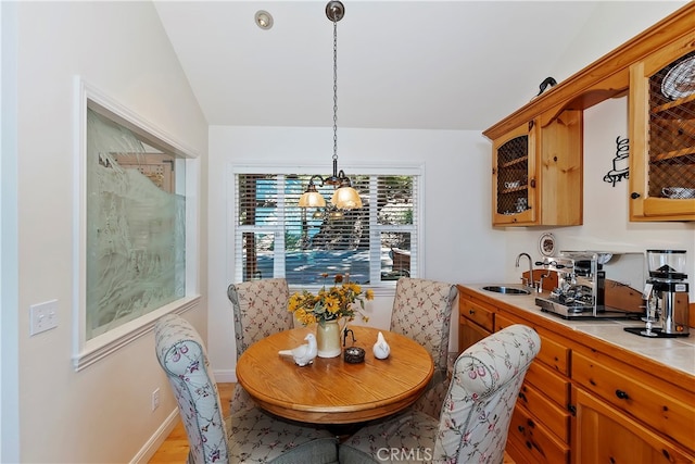 dining space featuring light hardwood / wood-style floors, a notable chandelier, lofted ceiling, and sink