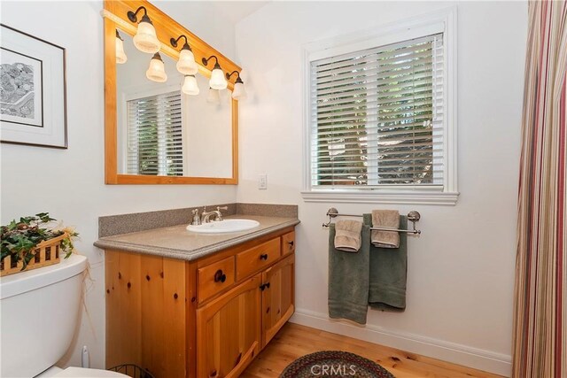 bathroom featuring vanity, hardwood / wood-style flooring, a healthy amount of sunlight, and toilet