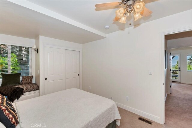 bedroom with a closet, ceiling fan, and light colored carpet