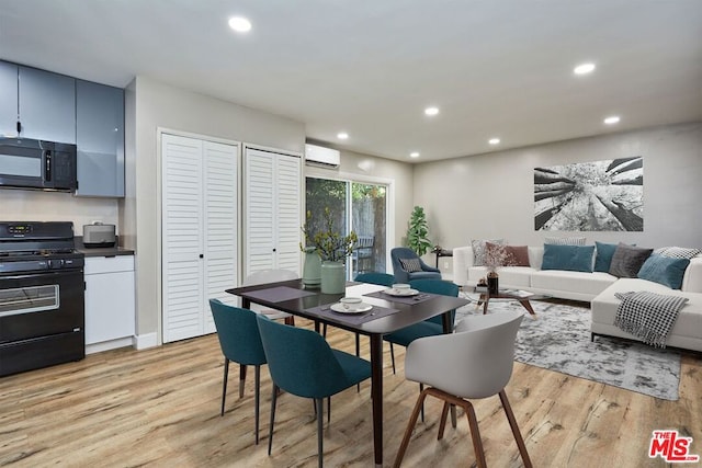 dining room with light hardwood / wood-style flooring and a wall unit AC