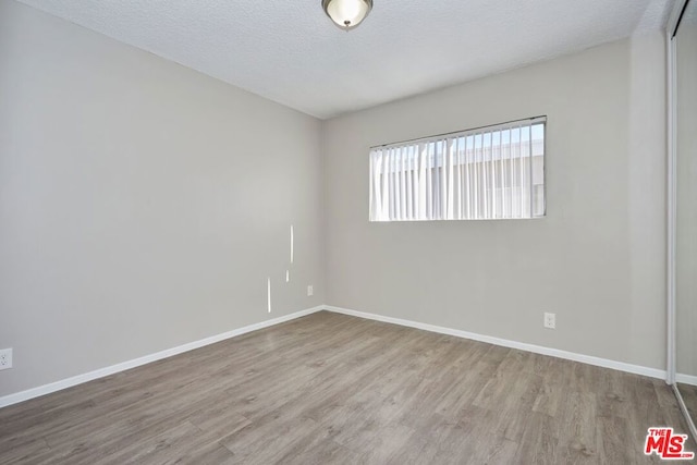 spare room featuring light hardwood / wood-style flooring and a textured ceiling