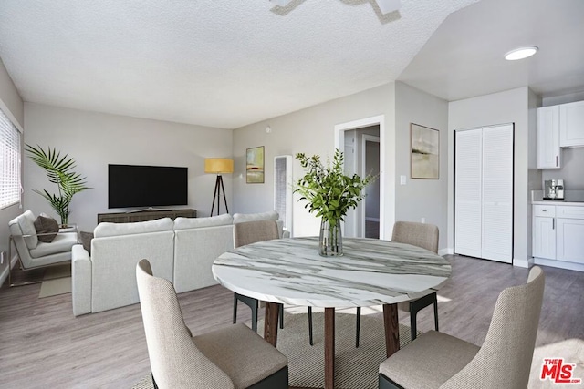 dining area featuring light wood-type flooring and a textured ceiling