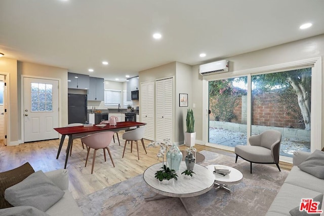 living room with light wood-type flooring and a wall unit AC