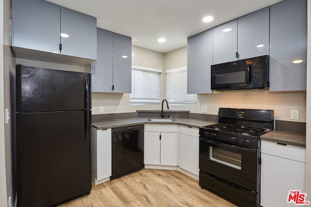 kitchen with black appliances, light hardwood / wood-style floors, white cabinetry, and sink