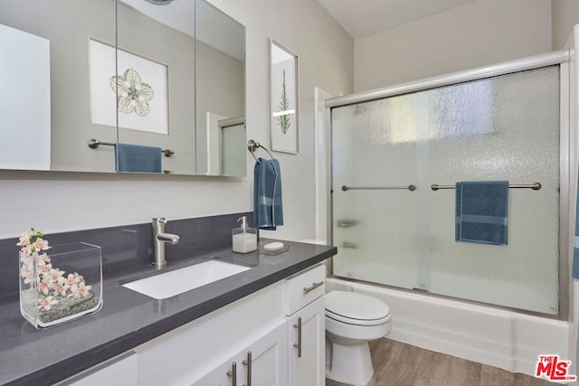 full bathroom featuring enclosed tub / shower combo, vanity, hardwood / wood-style floors, and toilet