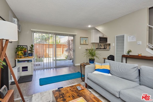 living room featuring light wood-type flooring and a textured ceiling