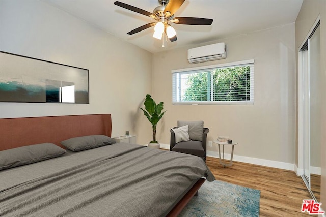 bedroom featuring a wall mounted AC, ceiling fan, light hardwood / wood-style flooring, and a closet