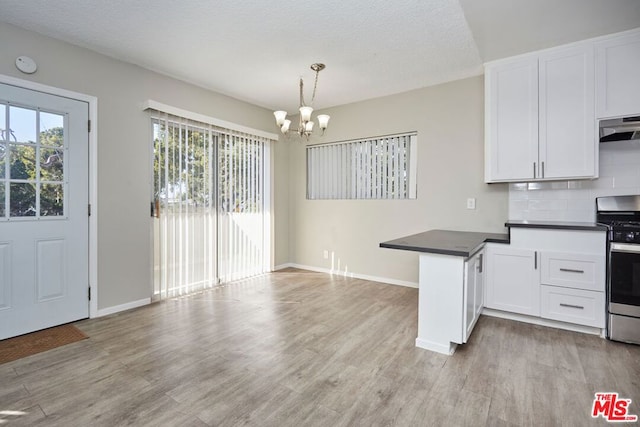 kitchen featuring light hardwood / wood-style floors, white cabinetry, stainless steel stove, and pendant lighting