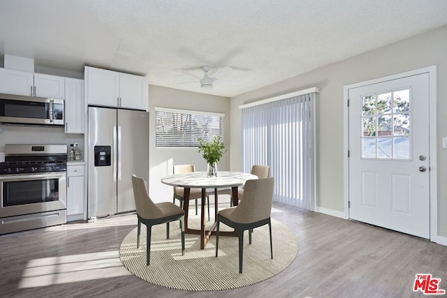 dining room with ceiling fan, a textured ceiling, and light hardwood / wood-style flooring