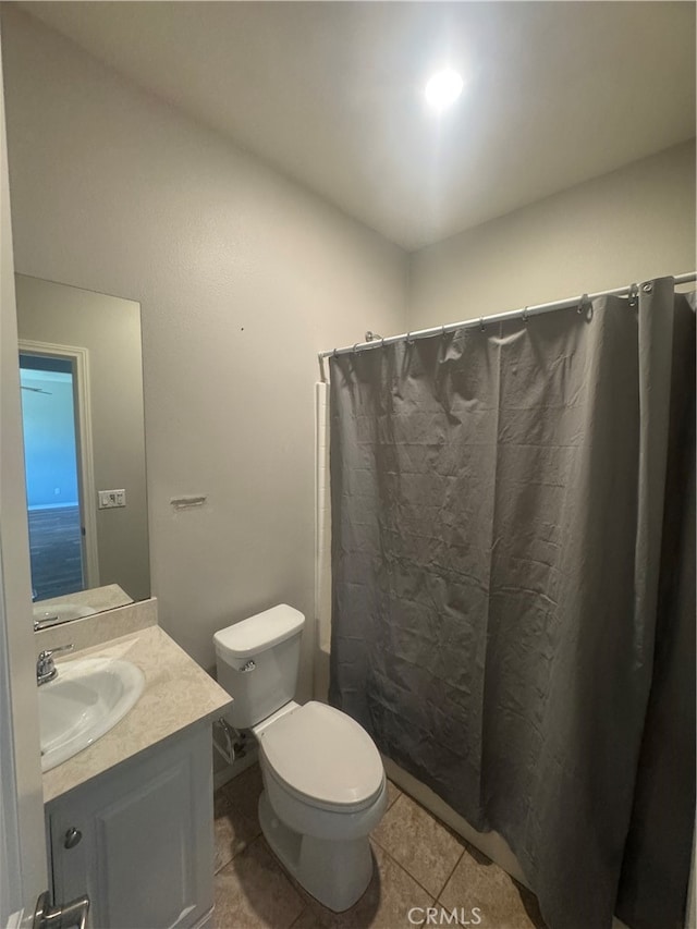 bathroom featuring curtained shower, tile patterned flooring, vanity, and toilet