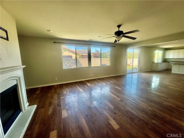 unfurnished living room featuring ceiling fan, dark hardwood / wood-style floors, and a healthy amount of sunlight