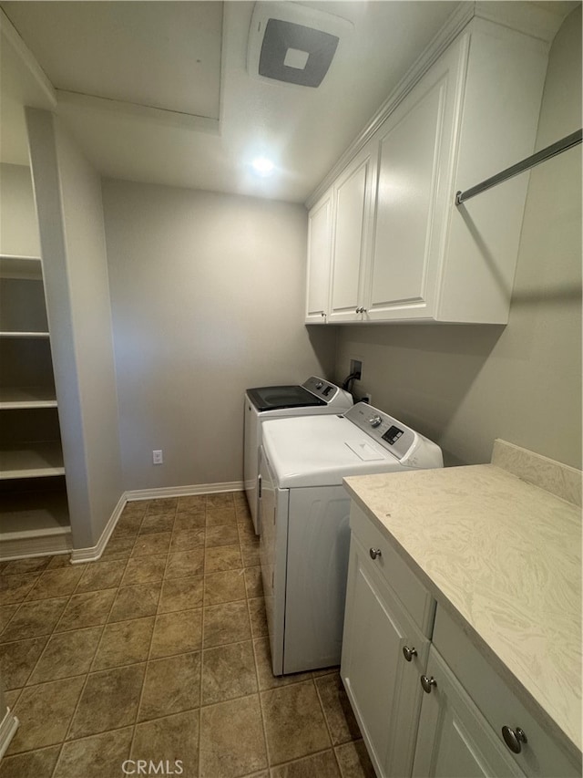 clothes washing area featuring cabinets, dark tile patterned flooring, and separate washer and dryer