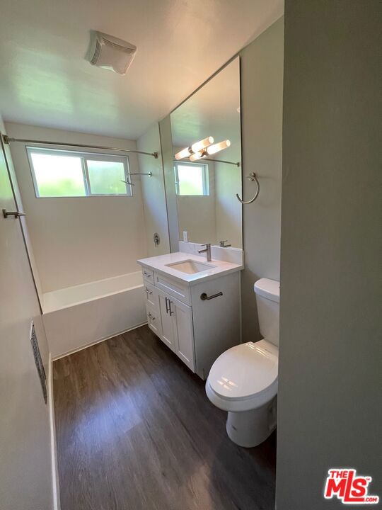 full bathroom with washtub / shower combination, hardwood / wood-style flooring, vanity, and toilet