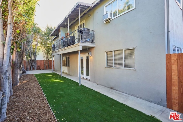 rear view of property featuring cooling unit, a balcony, a yard, and a patio