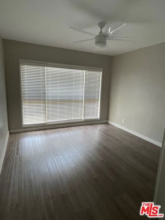 empty room featuring ceiling fan and dark hardwood / wood-style flooring