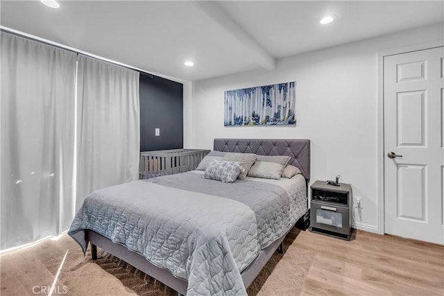 bedroom with light wood-type flooring and beamed ceiling