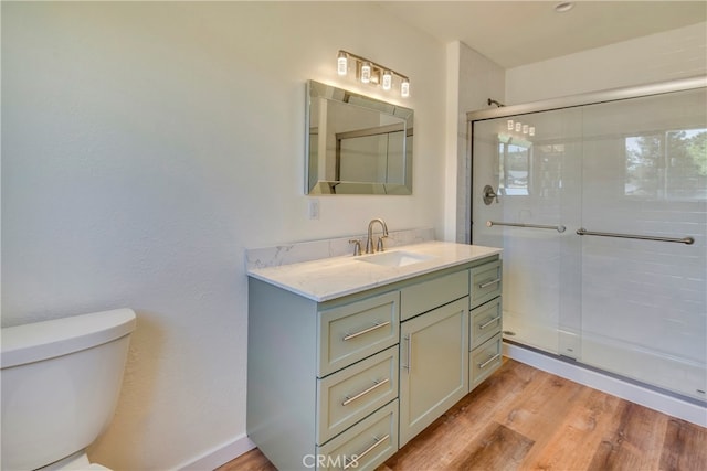 bathroom featuring hardwood / wood-style floors, vanity, toilet, and a shower with door