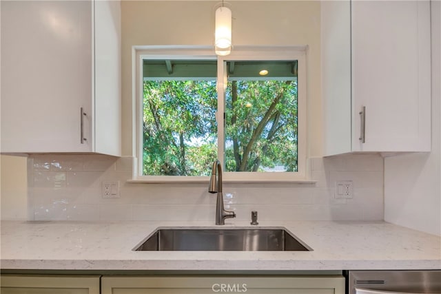 kitchen with a healthy amount of sunlight, decorative backsplash, sink, and light stone counters