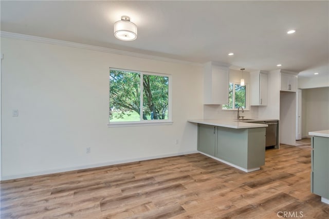 kitchen featuring light wood-type flooring, white cabinetry, kitchen peninsula, hanging light fixtures, and crown molding