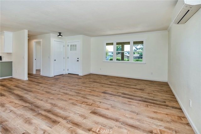 unfurnished living room featuring light wood-type flooring, ornamental molding, and a wall mounted AC