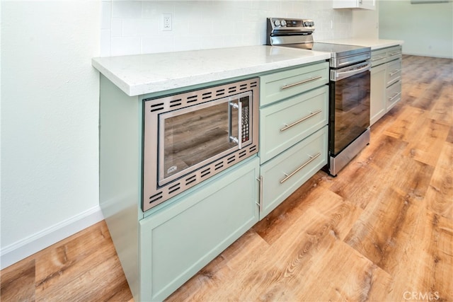 kitchen with light hardwood / wood-style flooring, backsplash, appliances with stainless steel finishes, and light stone counters