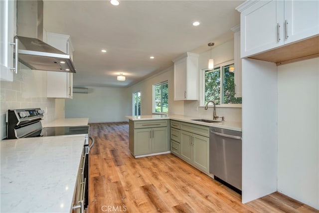 kitchen featuring hanging light fixtures, range, ventilation hood, dishwasher, and light hardwood / wood-style floors