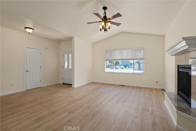 unfurnished living room with light hardwood / wood-style floors, ceiling fan, vaulted ceiling, and a fireplace