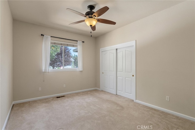 unfurnished bedroom featuring a closet, ceiling fan, and light colored carpet