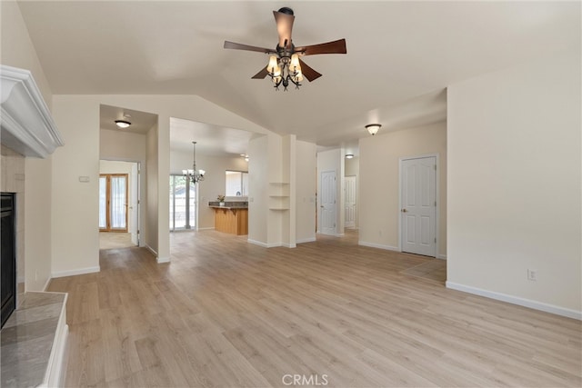 unfurnished living room featuring ceiling fan with notable chandelier, a fireplace, lofted ceiling, and light hardwood / wood-style flooring