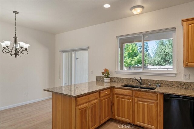 kitchen featuring light hardwood / wood-style floors, dishwasher, stone counters, sink, and a notable chandelier