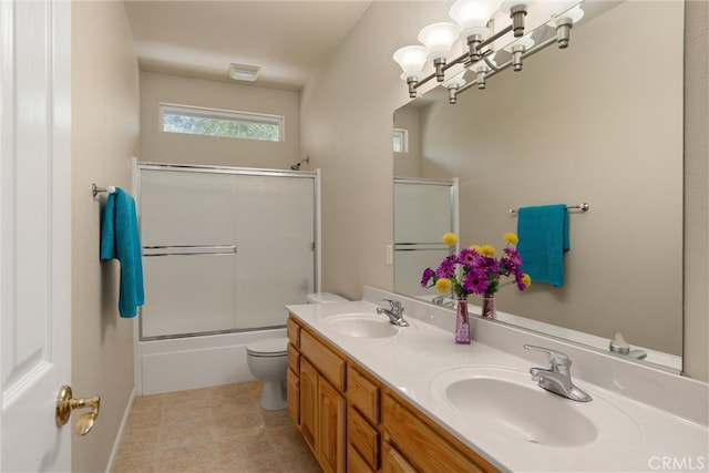 full bathroom with tile patterned floors, bath / shower combo with glass door, vanity, and toilet