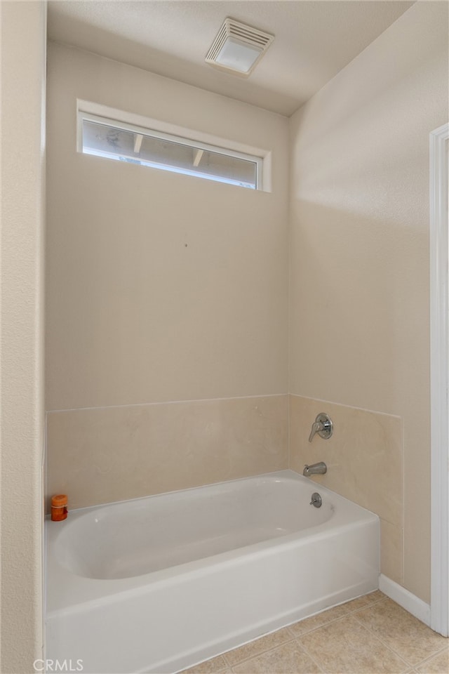 bathroom with a wealth of natural light, tile patterned flooring, and a bath