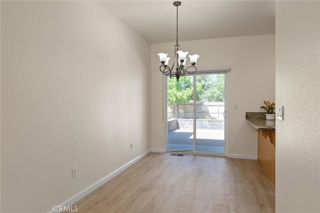 unfurnished dining area featuring light hardwood / wood-style floors and a notable chandelier