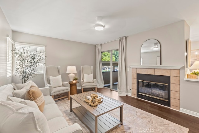 living room featuring wood-type flooring and a tiled fireplace