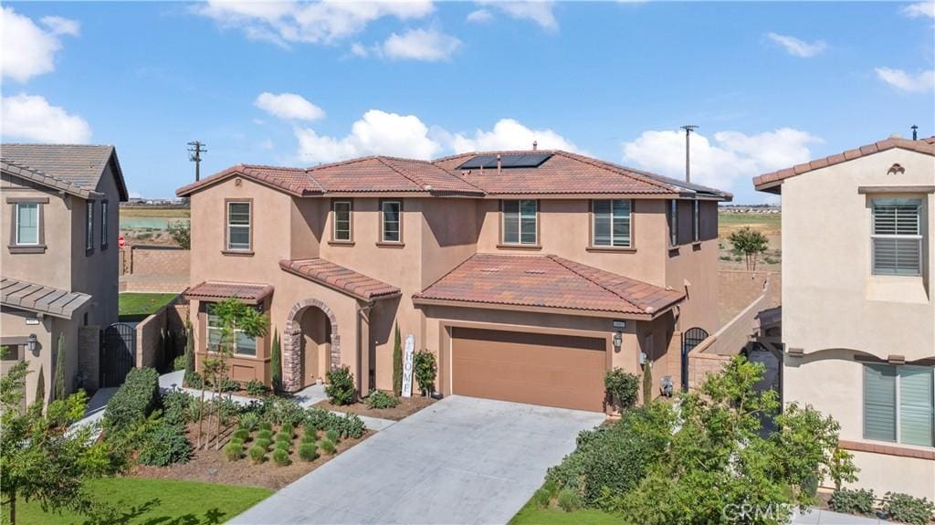 mediterranean / spanish-style home with solar panels and a garage