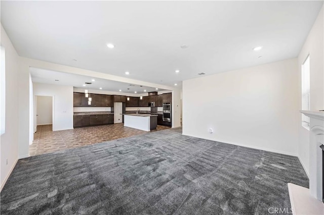 unfurnished living room featuring dark carpet and sink