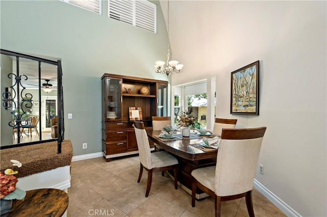 dining room with ceiling fan with notable chandelier, light tile patterned floors, and a high ceiling