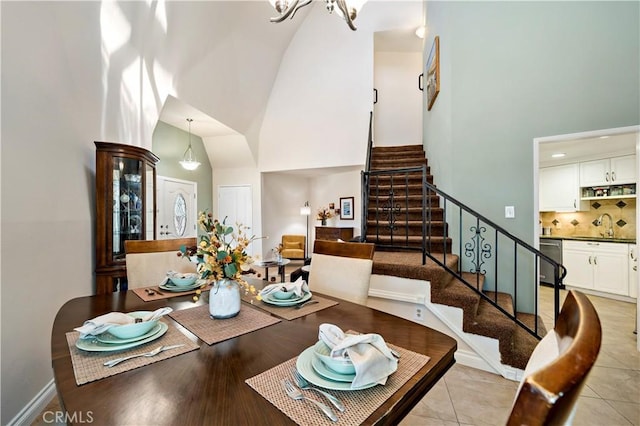 dining space with light hardwood / wood-style flooring, sink, high vaulted ceiling, and a chandelier