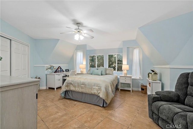 tiled bedroom with ceiling fan, a closet, and vaulted ceiling