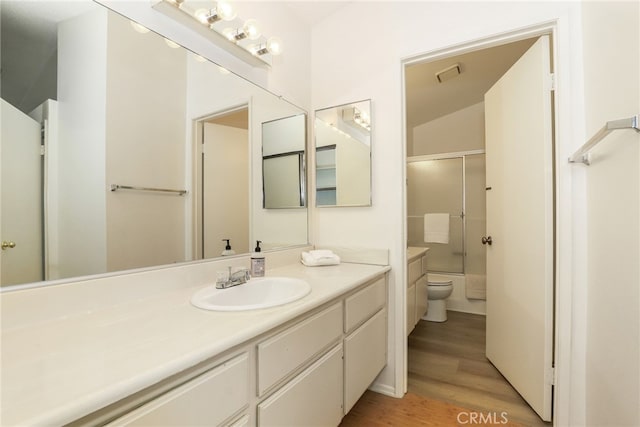 bathroom with a shower with door, toilet, vanity, and hardwood / wood-style flooring