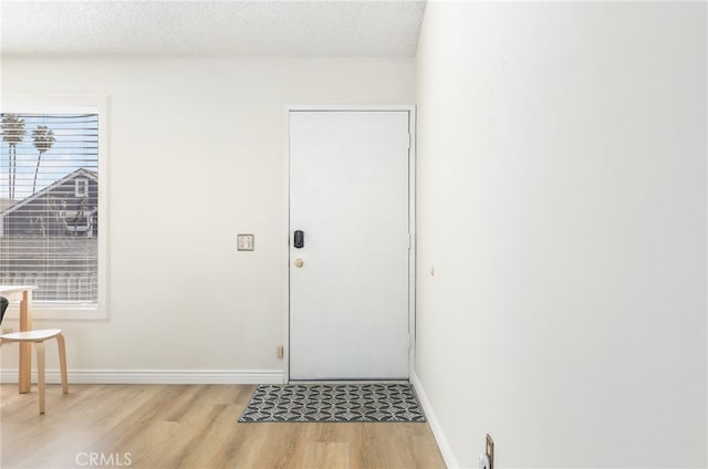 foyer entrance featuring light hardwood / wood-style flooring and a textured ceiling