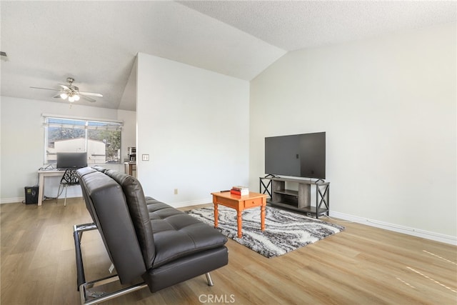 living room with light wood-type flooring, vaulted ceiling, ceiling fan, and a textured ceiling