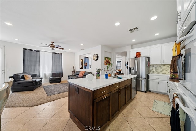 kitchen featuring stainless steel refrigerator with ice dispenser, light tile patterned floors, light countertops, visible vents, and white cabinets