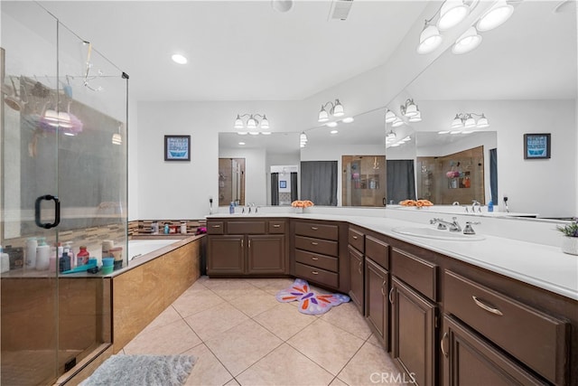 full bathroom featuring a stall shower, tile patterned flooring, a garden tub, and a sink