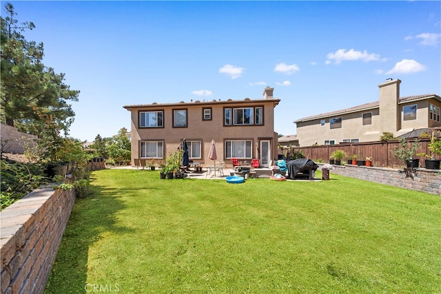 rear view of property with a patio, a lawn, and a fenced backyard