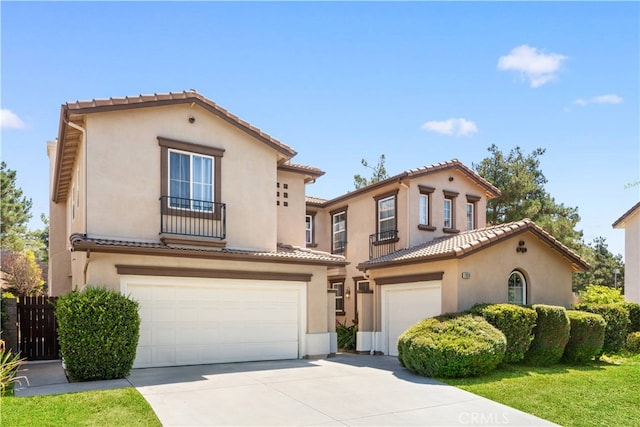 mediterranean / spanish home with concrete driveway, an attached garage, a tiled roof, and stucco siding