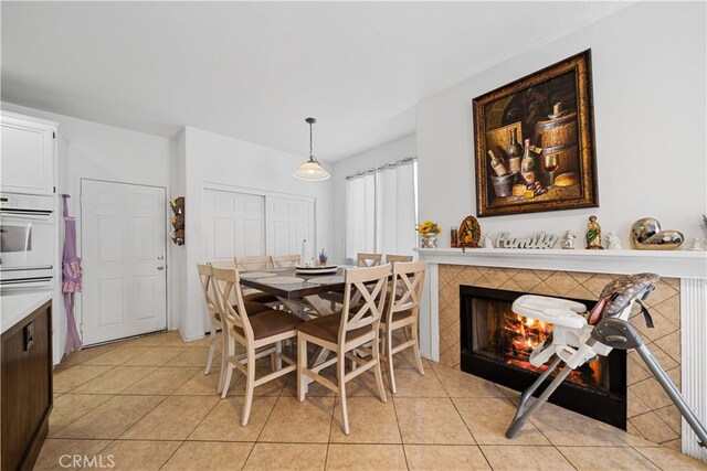 dining room with light tile patterned flooring and a fireplace